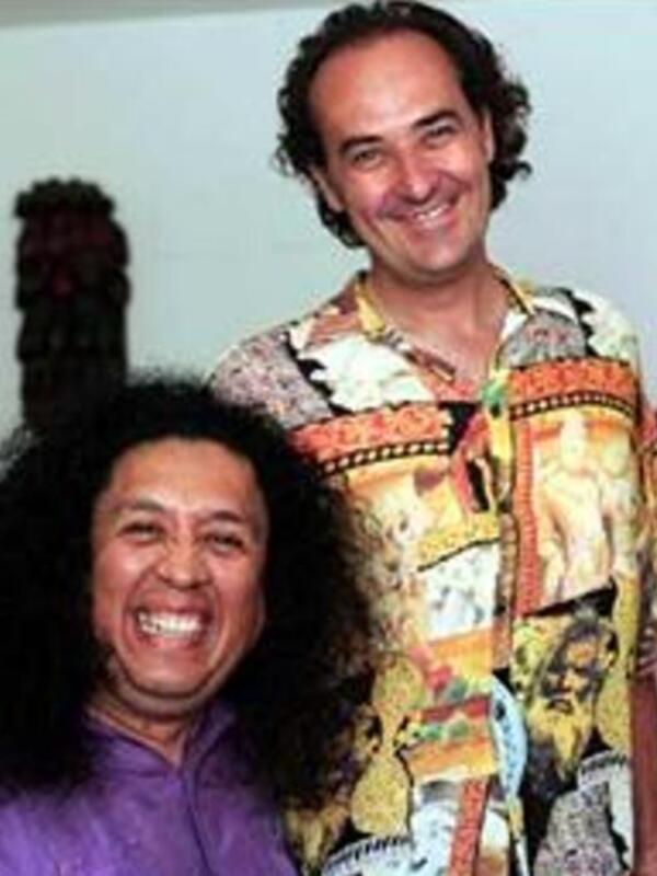 Dos hombres sonrientes, uno con cabello largo y el otro con una camisa hawaiana.