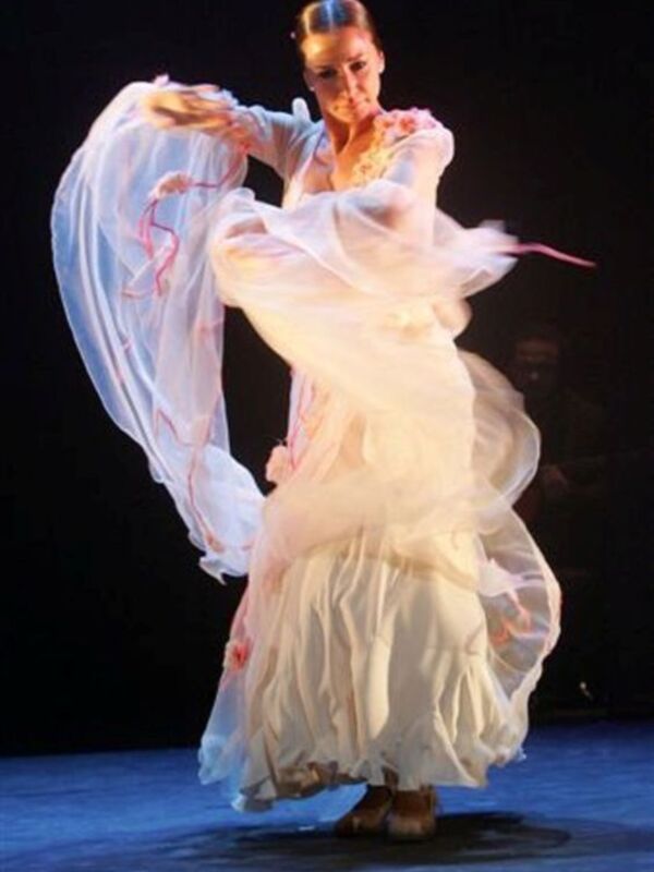 Danza clásica con vestimenta fluida y elegante, en escenario iluminado.
