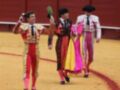 Tres toreros caminan en la plaza de toros, cada uno con un colorido traje y una espada.
