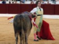 Un torero se prepara para el encierro en una plaza de toros, con un toro en el centro del ruedo.