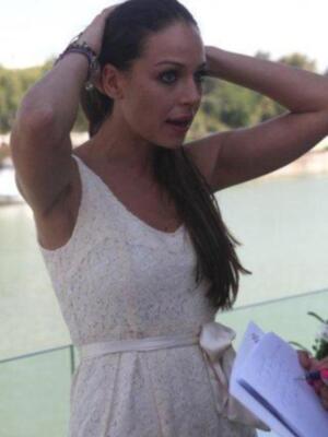 Una mujer con vestido blanco y cabello largo, posando en un entorno al aire libre.