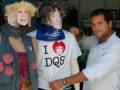Personas posando con máscaras de personajes famosos y una camiseta 'I ❤️ DQS' en una tienda.