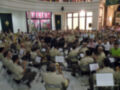 Concierto militar en un salón de eventos con músicos tocan instrumentos.