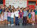 Equipo de natación y niños posando en una piscina municipal.