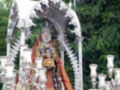 Procesión religiosa con imagen de Virgen en plata y flores blancas.