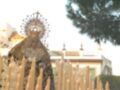 Una procesión religiosa con una figura vestida en traje tradicional, rodeada de numerosas velas encendidas. Se observa un ambiente festivo y ceremonial, típico de celebraciones religiosas en ciertas culturas.