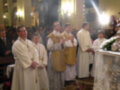 Celebración religiosa en una iglesia con sacerdotes y fieles participando en una ceremonia.