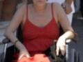 Una mujer en silla de ruedas, con una camiseta roja y un bolso negro.