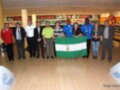 Equipo celebrando en un centro de bowling con una bandera regional.