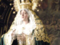 Imagen de una Virgen con vestimenta tradicional, coronada y rodeada por estrellas. Contexto religioso o devocional.