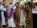 Imaginación de una ceremonia religiosa en una iglesia, con dos personas vestidas con vestidos de color blanco y negro, posiblemente sacerdotes, frente a una mesa con flores y un altar.