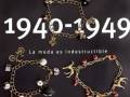 Bracelete con colgantes de diferentes tamaños y colores, sobre fondo negro. Texto: 1940-1949 La moda es indestructible.