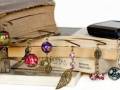 Llaveros con colgantes de diferentes formas y colores sobre libros antiguos.