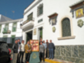 Un grupo de personas posa frente a una casa típica andaluza con detalles arquitectónicos tradicionales.