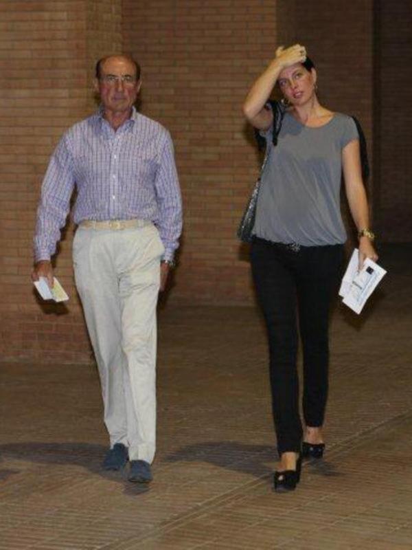 Dos personas caminando juntas en un entorno urbano con un fondo de pared de ladrillo rojo.