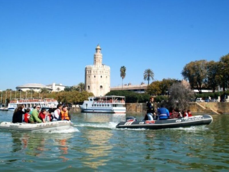 Puerto de Sevilla con el Torre del Oro al fondo. Barcos navegando en el río Guadalquivir.