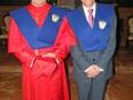 Dos hombres vestidos con trajes ceremoniales; uno con un manto rojo y el otro con un chaleco azul. Ambos parecen estar en una ceremonia formal, posiblemente religiosa o académica.