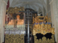 Interior de una iglesia con altares dorados, velas encendidas y decoraciones religiosas.