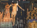 Imagen de un crucificado en una iglesia, rodeado de velas y decoración.