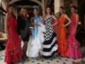Seis mujeres posan con elegantes vestidos de flamenca en un ambiente sofisticado.