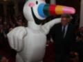 Un personaje inflable de un unicornio con una trompa colorida, posiblemente representando a "Igloo", se encuentra entre una audiencia en un evento formal.