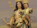 Estatua de una Virgen con un niño en sus brazos, vestida con una túnica dorada y azul, rodeada por un halo de oro.
