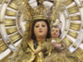 Imagen de la Virgen María con un niño en sus brazos, vestida con una vestidura dorada y coronada, rodeada por un halo de rayos dorados.