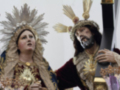 Estas imágenes muestran a una Virgen y un Cristo con vestimentas elaboradas, posiblemente en una iglesia o altar. La Virgen lleva un manto con detalles dorados y broches, mientras que el Cristo tiene una corona y un manto con insignias. La escena parece ser de la Semana Santa, una celebración religiosa importante en muchas culturas.