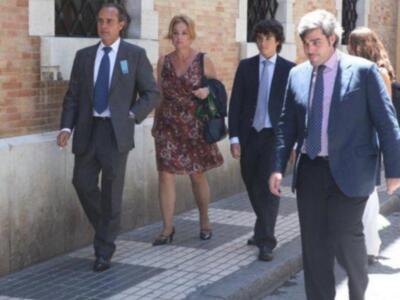 Una familia camina por una calle con casas de ladrillo. La madre lleva un vestido floral y un bolso, mientras los padres más jóvenes están en trajes. El padre de la imagen lleva una corbata azul y un cinturón negro.