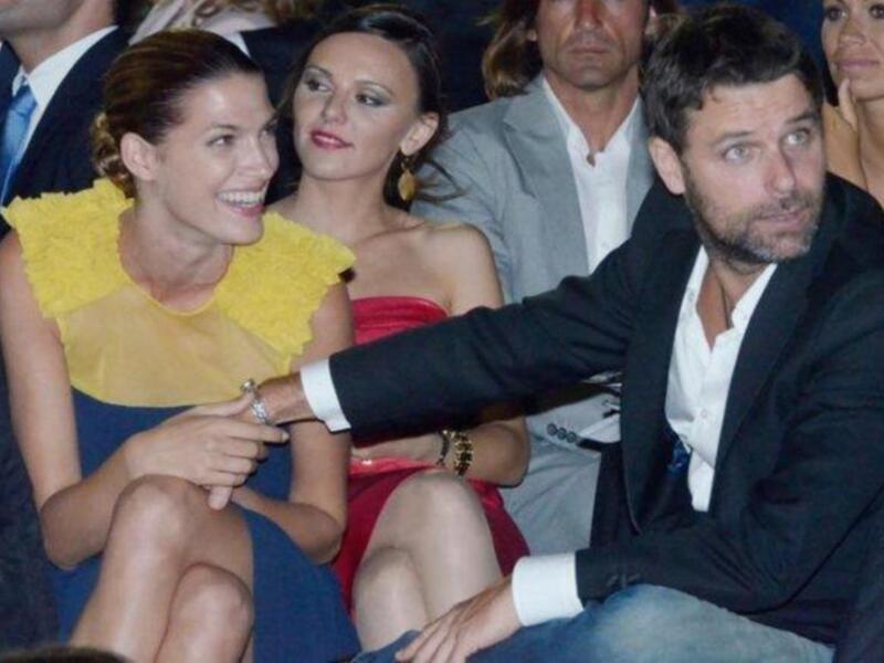 Persona en traje negro y mujer en vestido amarillo sentados juntos en un evento formal.