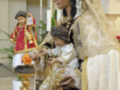 Imagen religiosa con una figura de la Virgen María y un niño Jesús, rodeados por adornos tradicionales.