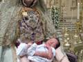 A una mujer vestida con una túnica y tocado, sosteniendo un bebé recién nacido. La escena se desarrolla en un ambiente religioso, con una estatua de la Virgen María y elementos dorados que sugieren un ambiente sagrado.