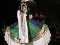 Actriz en traje tradicional de danza folclórica, con sombrero y vestido colorido, en escenario iluminado.
