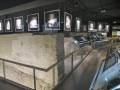Exposición histórica con paneles informativos y muros antiguos en un museo.