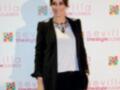 Una mujer con un look elegante, incluyendo un blazer negro, una camisa blanca y un collar de cristales, posando frente a un fondo con logos de 'The Style Outlets' y 'Sevilla'.