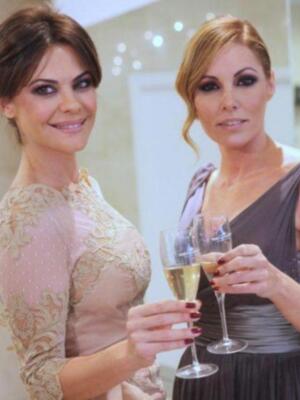 Dos mujeres en vestidos elegantes sostienen copas de champán, posiblemente en una celebración formal.