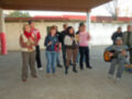 Una escena festiva en un patio cubierto, con personas vestidas de colores vivos y una persona tocando la guitarra.