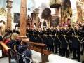 Una procesión religiosa en un templo con soldados uniformados y una mujer en silla de ruedas.