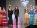 Desfile de moda flamenca con modelos en vestidos tradicionales y flores en el cabello.