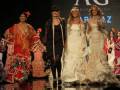 Desfile de moda flamenca con modelos vestidos de trajes tradicionales y vestidos blancos.