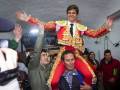 Festejo tradicional español con torero celebrando en hombros tras victoria en plaza de toros.