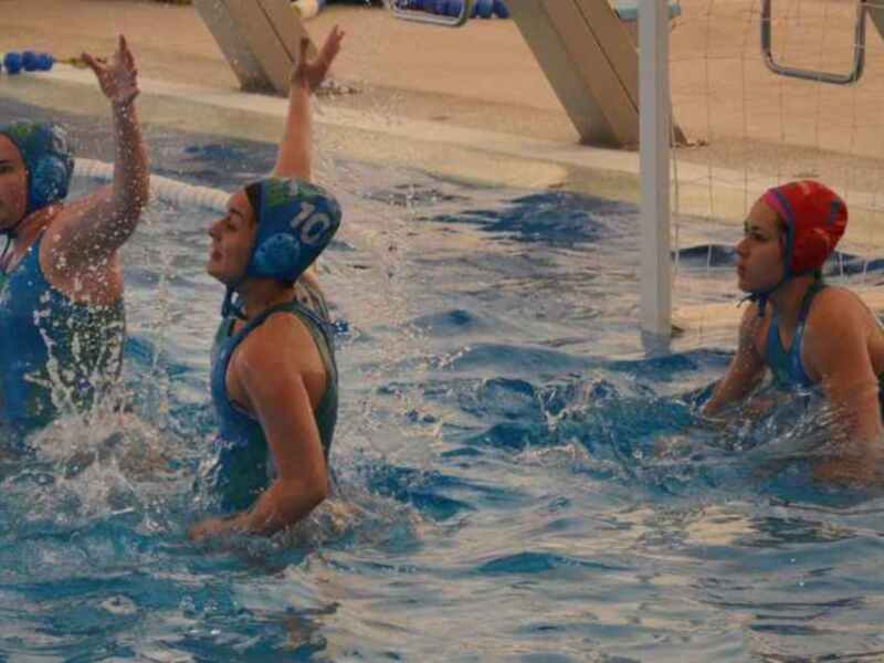 Jugadoras de waterpolo celebrando una anotación en una piscina.