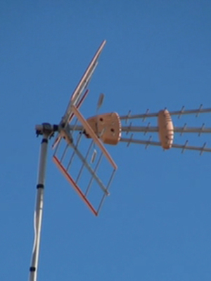 Un antena de televisión con varios elementos en un poste contra el cielo azul.