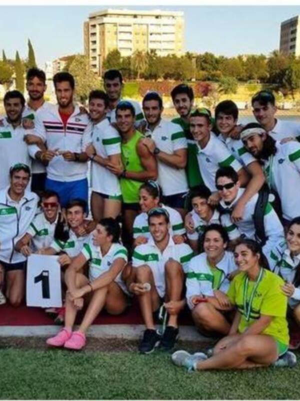 Equipo de fútbol celebrando una victoria en un estadio con el mar y edificios al fondo.