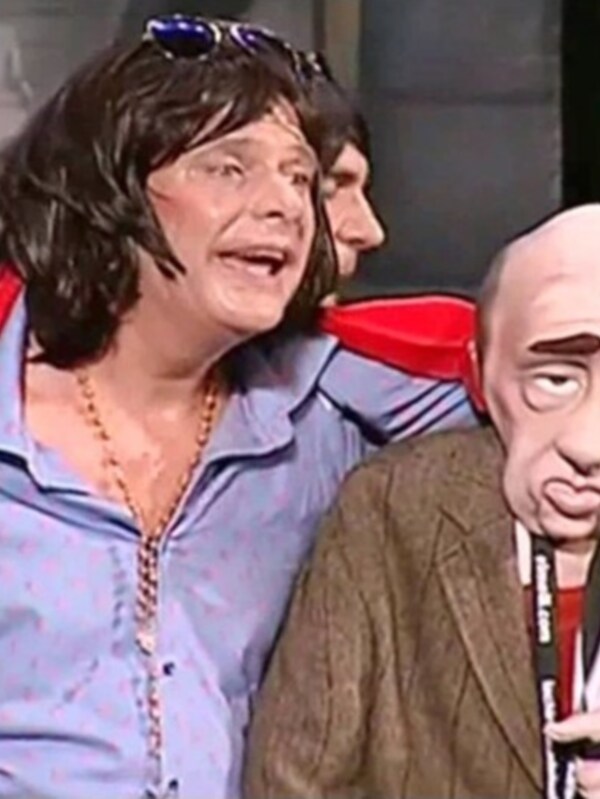 Dos personas en una escena cómica, uno con un traje rojo y la otra con una máscara de payaso.