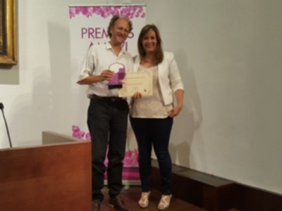 Premiación en una conferencia o evento, con un hombre y una mujer recibiendo un reconocimiento.
