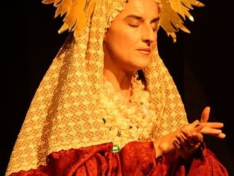 Una mujer con un atuendo dorado y rojo, posiblemente en una escena teatral o de cine.
