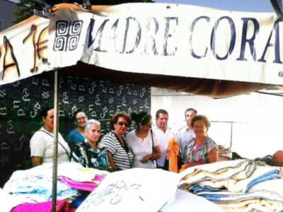 Personas sentadas en una mesa con mantel blanco y un cartel grande que dice "MADRE CORAJE".