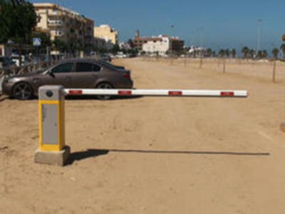 Vista de una playa con una barra de seguridad y un coche estacionado en el fondo.