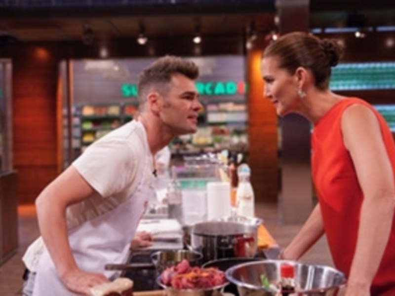 Un chef en un programa de cocina con una presentadora en un entorno de cocina profesional.
